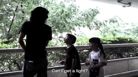 A still image from a video of two small children asking an adult for a light